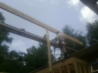 Carpenter setting a ridge beam over a new addition frame — Ice Dam Removal by Roofing Brothers in Little Falls