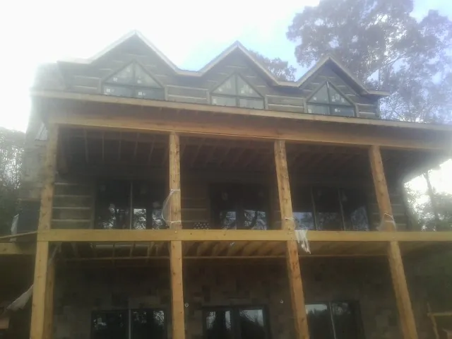 Dormers and porch framing on a large log home under construction — Roof Coating work by our crew in Little Falls