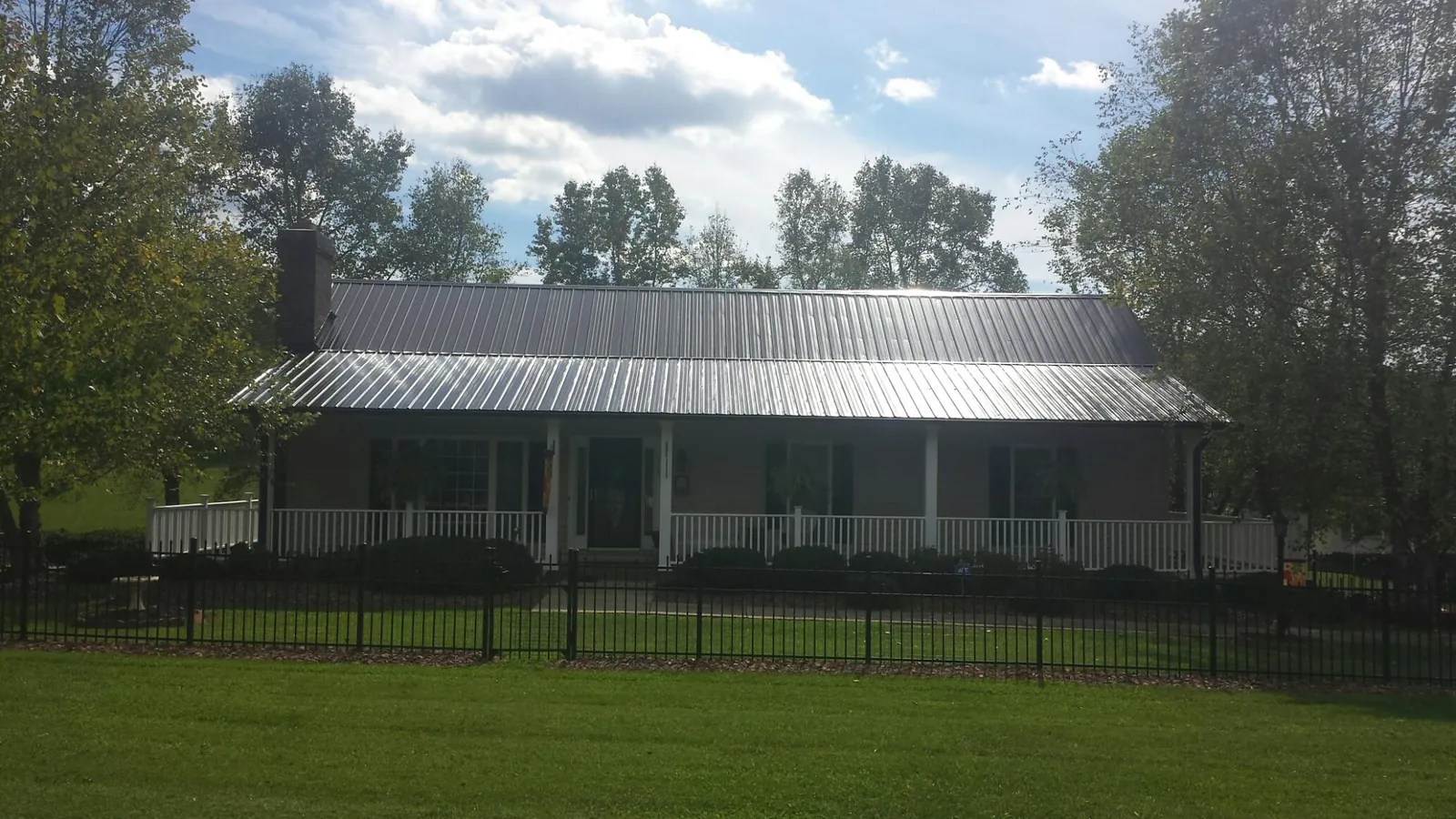 Gray metal roof on a brick ranch with a full width front porch — Gutter Guard Installation work by our crew in Little Falls